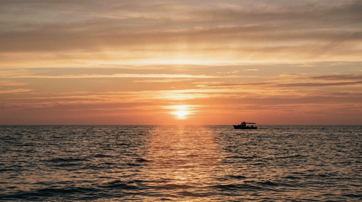 Low sun over the Gulf of Mexico with a tour boat silhouetted on the water during a sunset Anna Maria Island dolphin tour